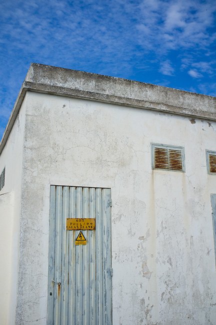 Weathered building, electrical sign and blue sky. Weathered building, electrical sign and blue sky.