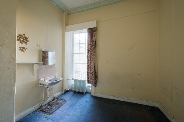 Derelict room with sink and faded carpet